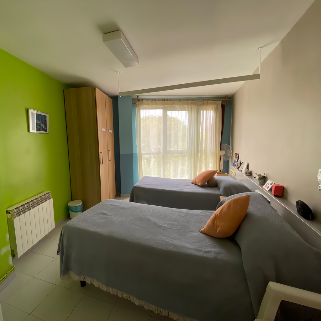 Habitación luminosa de la residencia con dos camas bien hechas y cojines decorativo