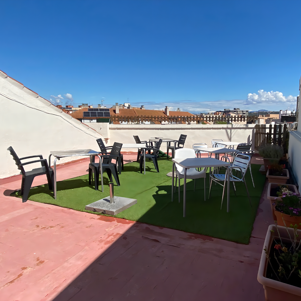 Vista panorámica de la terraza de nuestra residencia, equipada con césped artificial, cómodas sillas y mesas para disfrutar al aire libre
