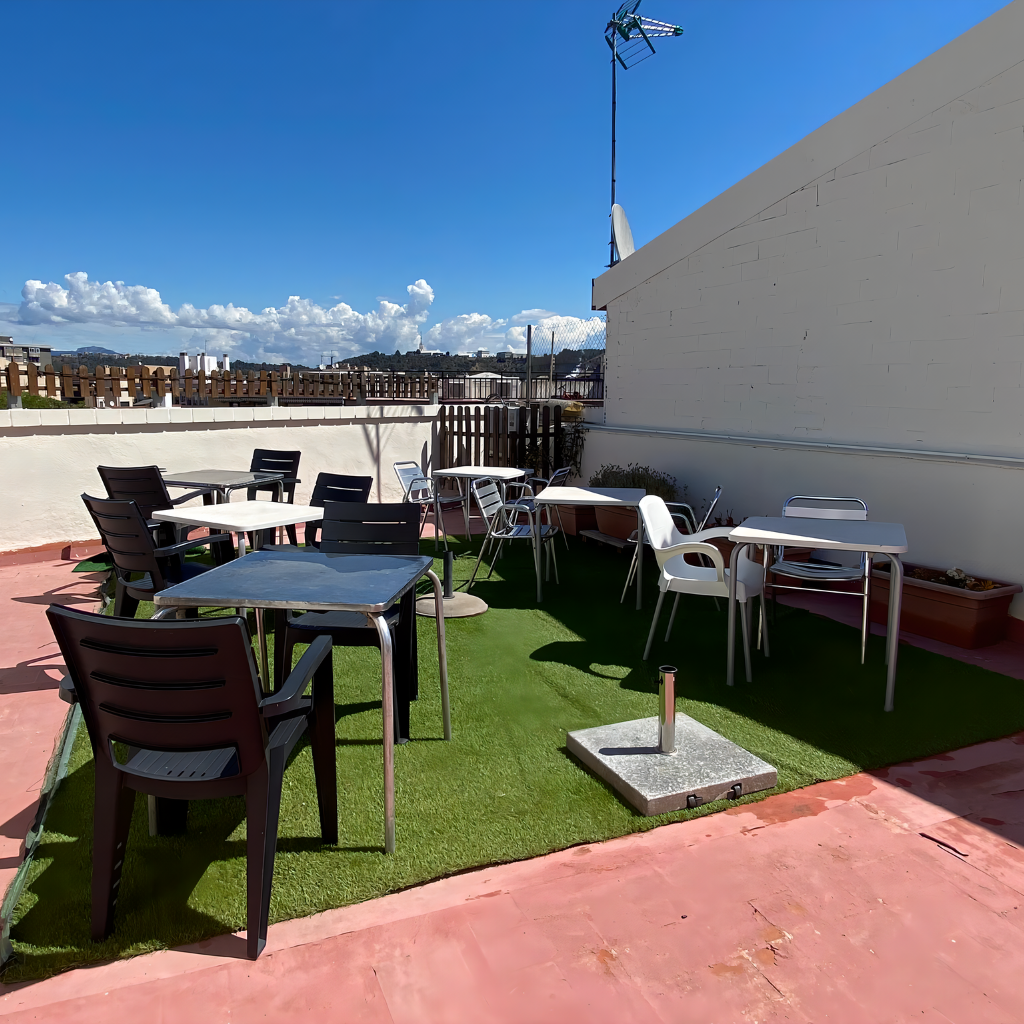 Vista panorámica de la terraza de nuestra residencia, equipada con césped artificial, cómodas sillas y mesas para disfrutar al aire libre